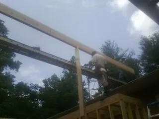 Carpenter setting a ridge beam over a new addition frame — Ice Dam Removal by Roofing Brothers in Brent