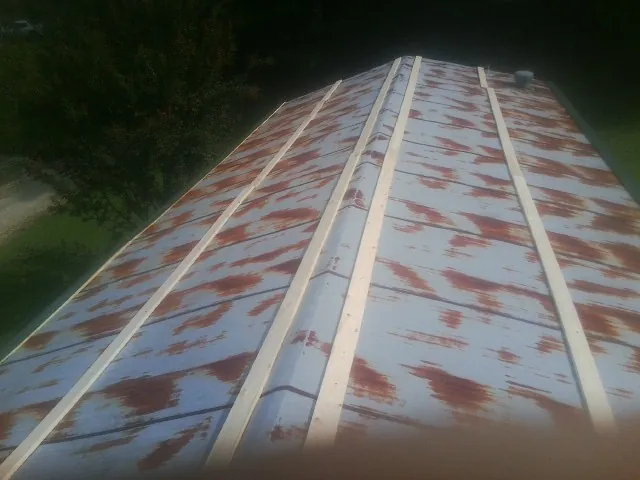 Rusted metal roof panels with new wood purlins before replacement — Storm Damage Roof Repair in Brent by Roofing Brothers