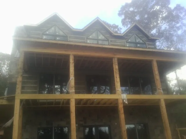 Dormers and porch framing on a large log home under construction — Roof Coating work by our crew in Brent