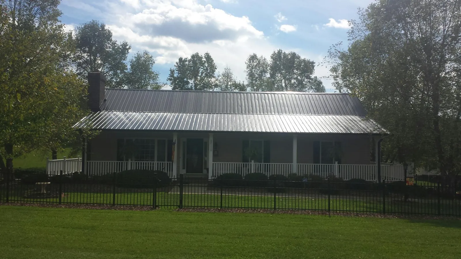 Gray metal roof on a brick ranch with a full width front porch — Gutter Guard Installation work by our crew in Brent