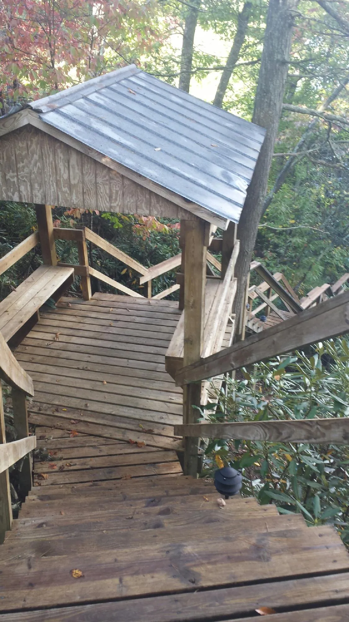 Metal roofed shelter over wooden steps on a wooded walkway — Skylight Repair & Installation work by our crew in Brent