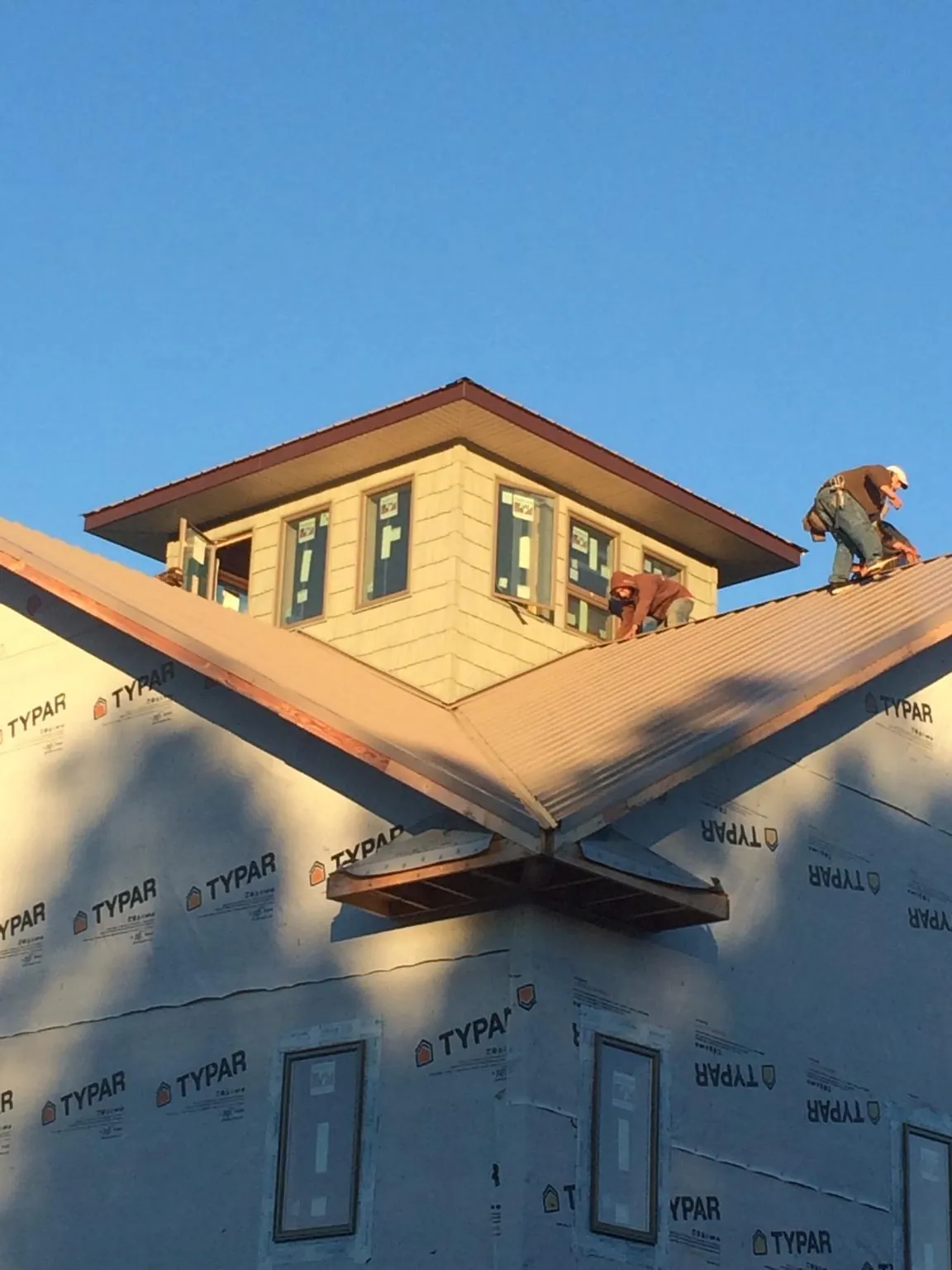 Roofers working around a rooftop cupola on a new metal roof at sunset — Roof Waterproofing in Brent by Roofing Brothers